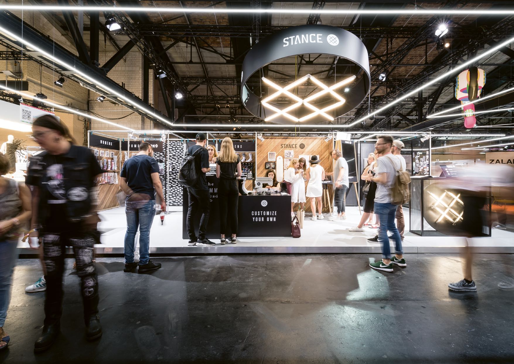 Moderner Messestand von STANCE auf der Bread & Butter Messe, gestaltet von MORE PIOUS STUDIOS, mit auffälliger Beleuchtung und individueller Sockendesign-Station.