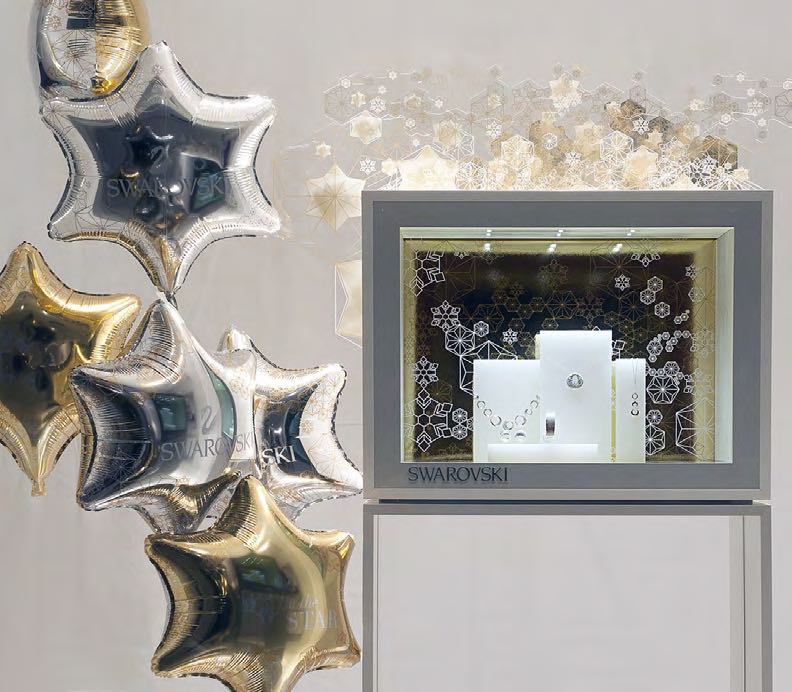 Swarovski Schaufenster mit Schmuckdisplay und goldenen Ballonsternen, gestaltet von MORE PIOUS STUDIOS